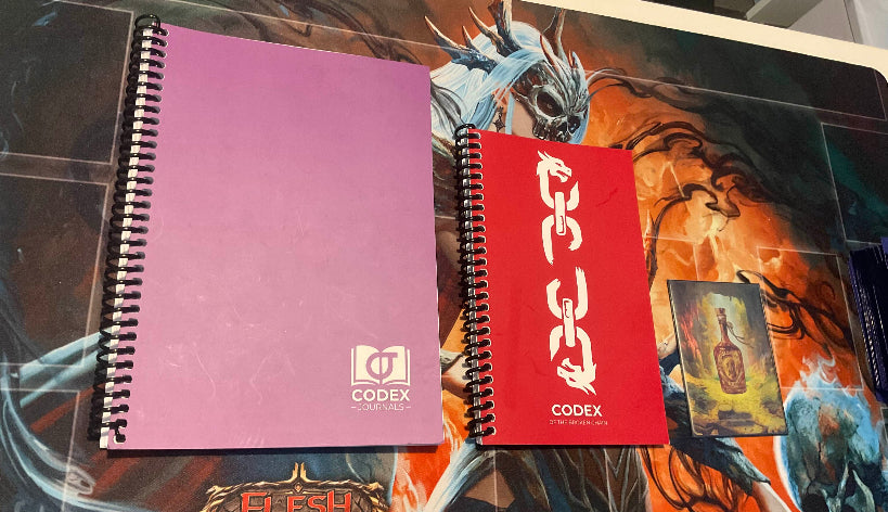 Side-by-side comparison of the standard Codex Journal and the smaller Challenger Edition, highlighting portability and scaled-down format for competitive play.